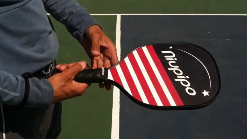 black and red pickleball paddle in the hand of player