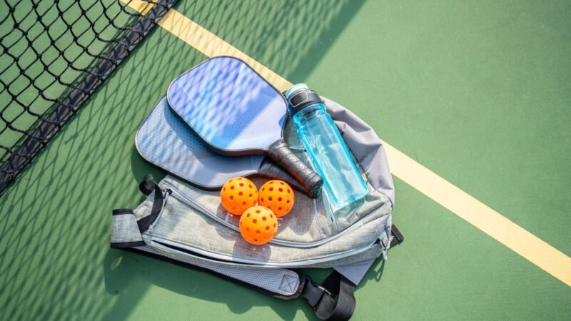 pickleball paddles with balls and bags on at the court with the bottle of water