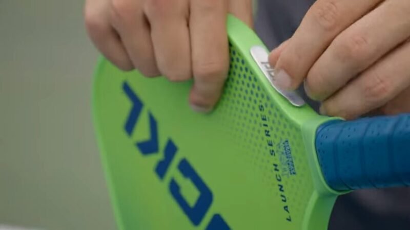 placing lead tape on a green pickleball paddle